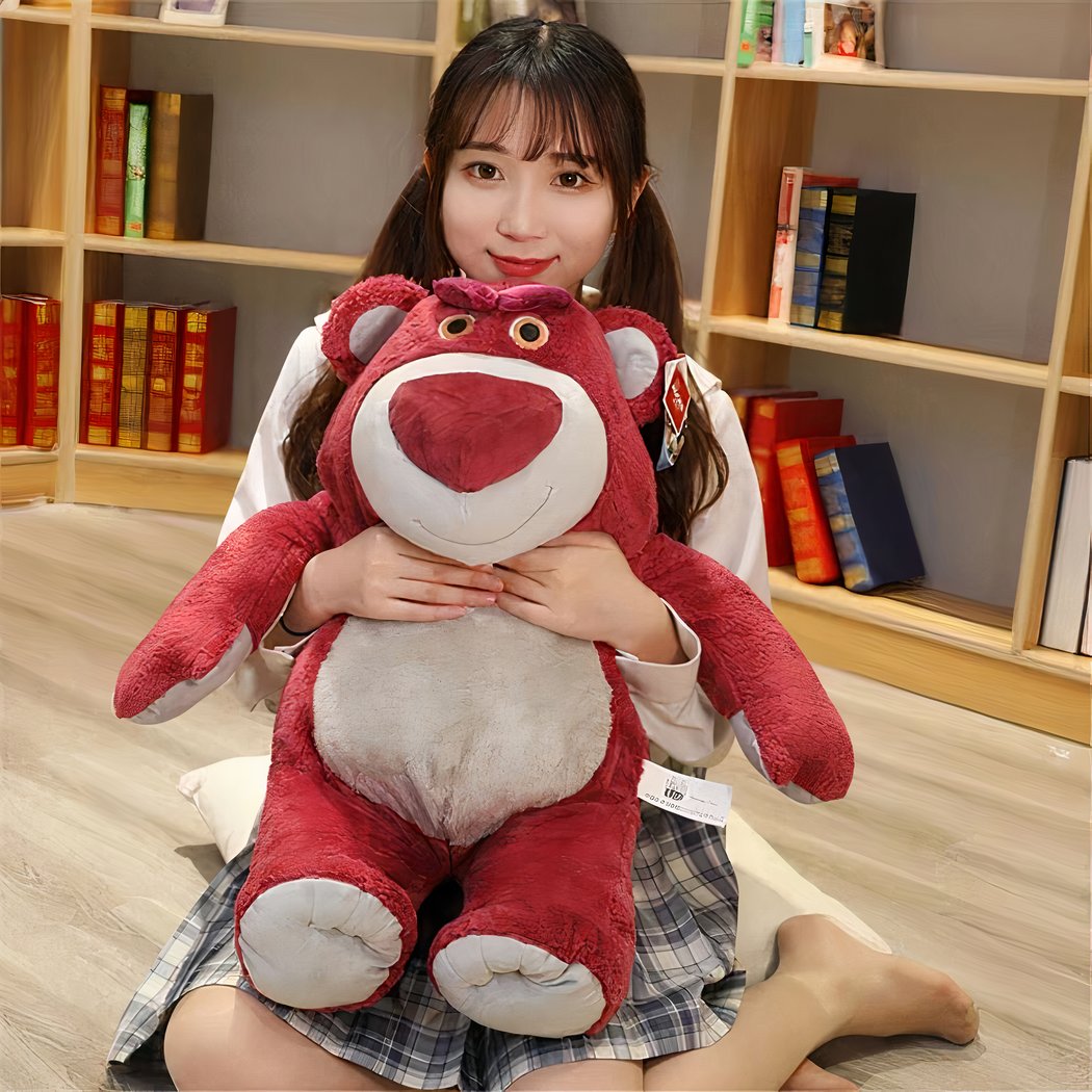 Young woman sitting on the floor, hugging a giant Lotso Toy Story plush bear