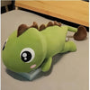 Green kawaii dinosaur plush with brown spikes, big eyes, pink cheek, lying on a book.
