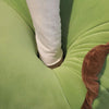 Kawaii green dinosaur plush with white leg and brown tail on lime-green fabric.